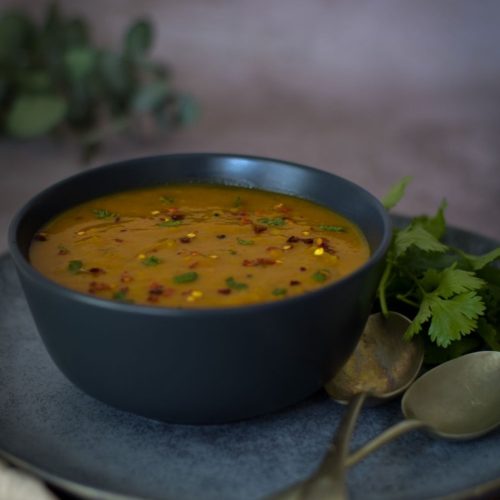 Masala Dal in a black bowl with spoons on the right side