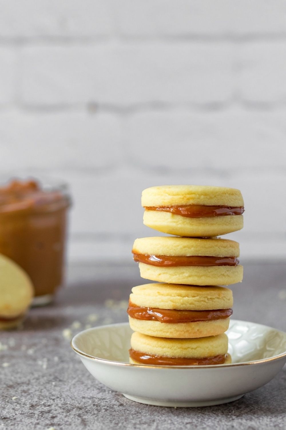 Dulce de Leche cookies stacked on a small plate with caramel at the left back