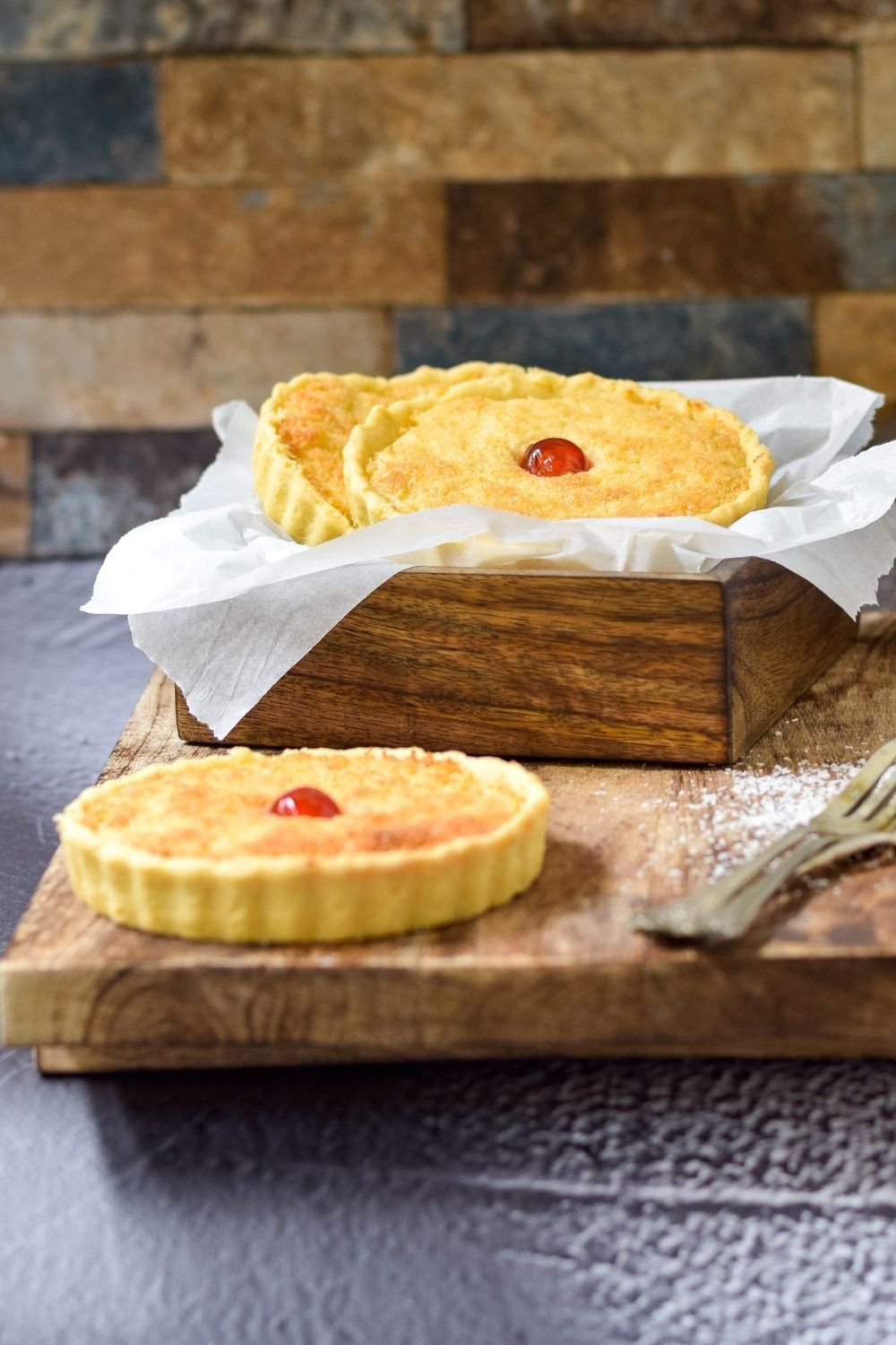 Hong Kong Coconut Tarts in a wooden box and one on a wooden board