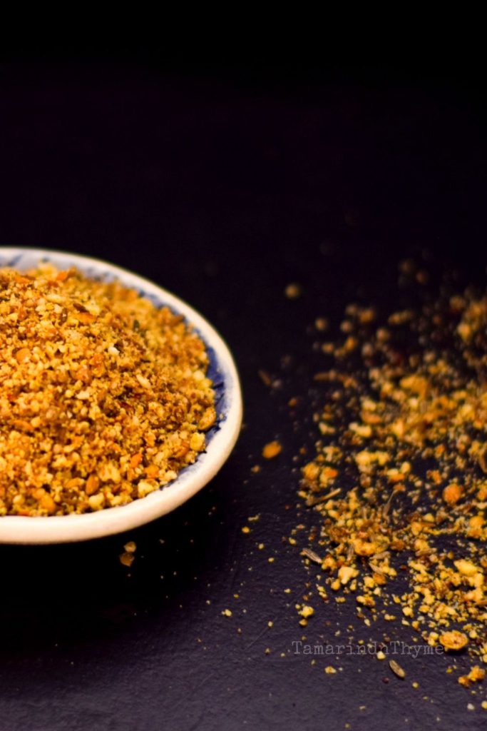 Egyptian spice mix Dukkah in a white bowl with spoons of spice in front