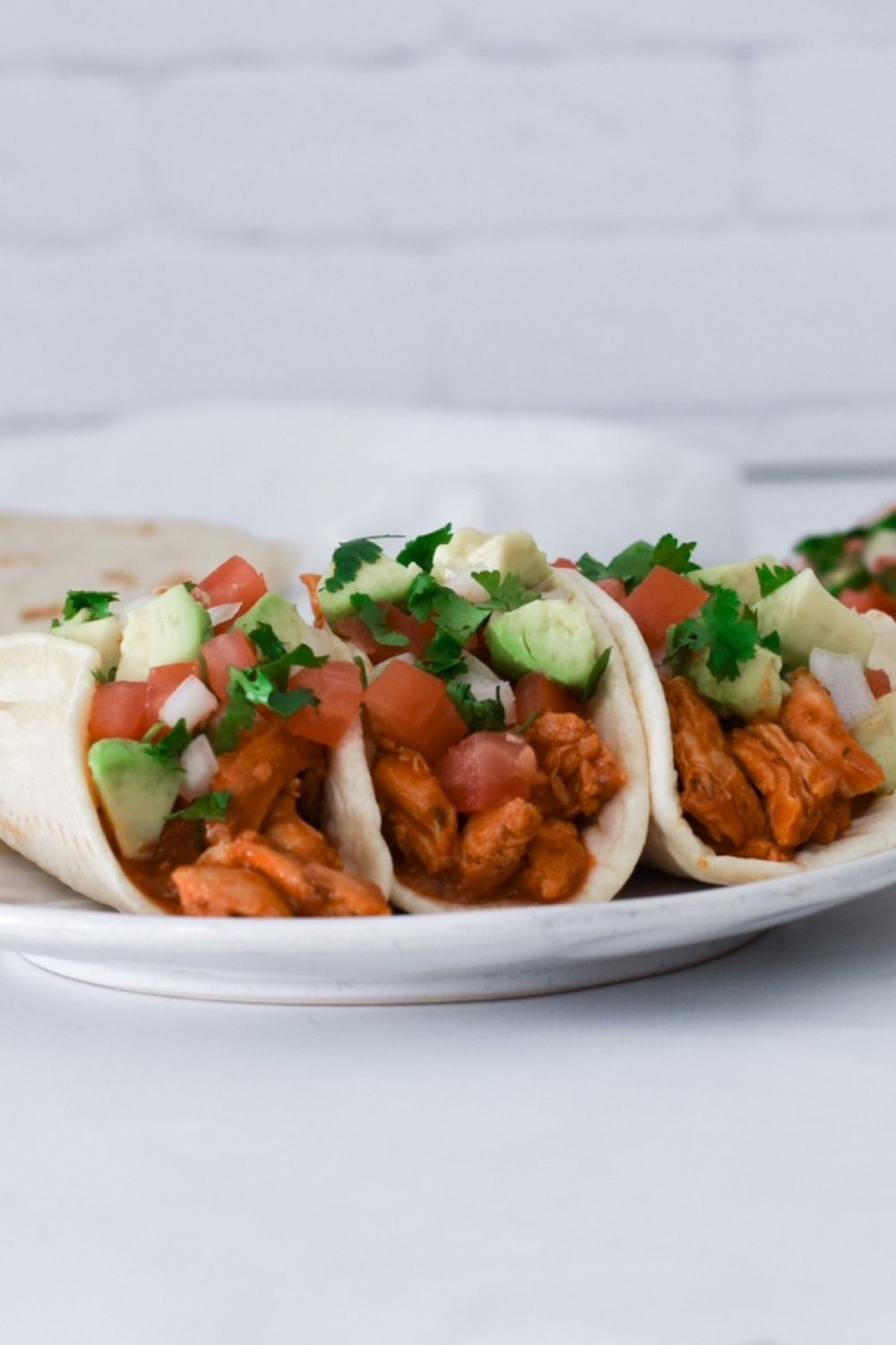 saucy chicken tacos in a white plate