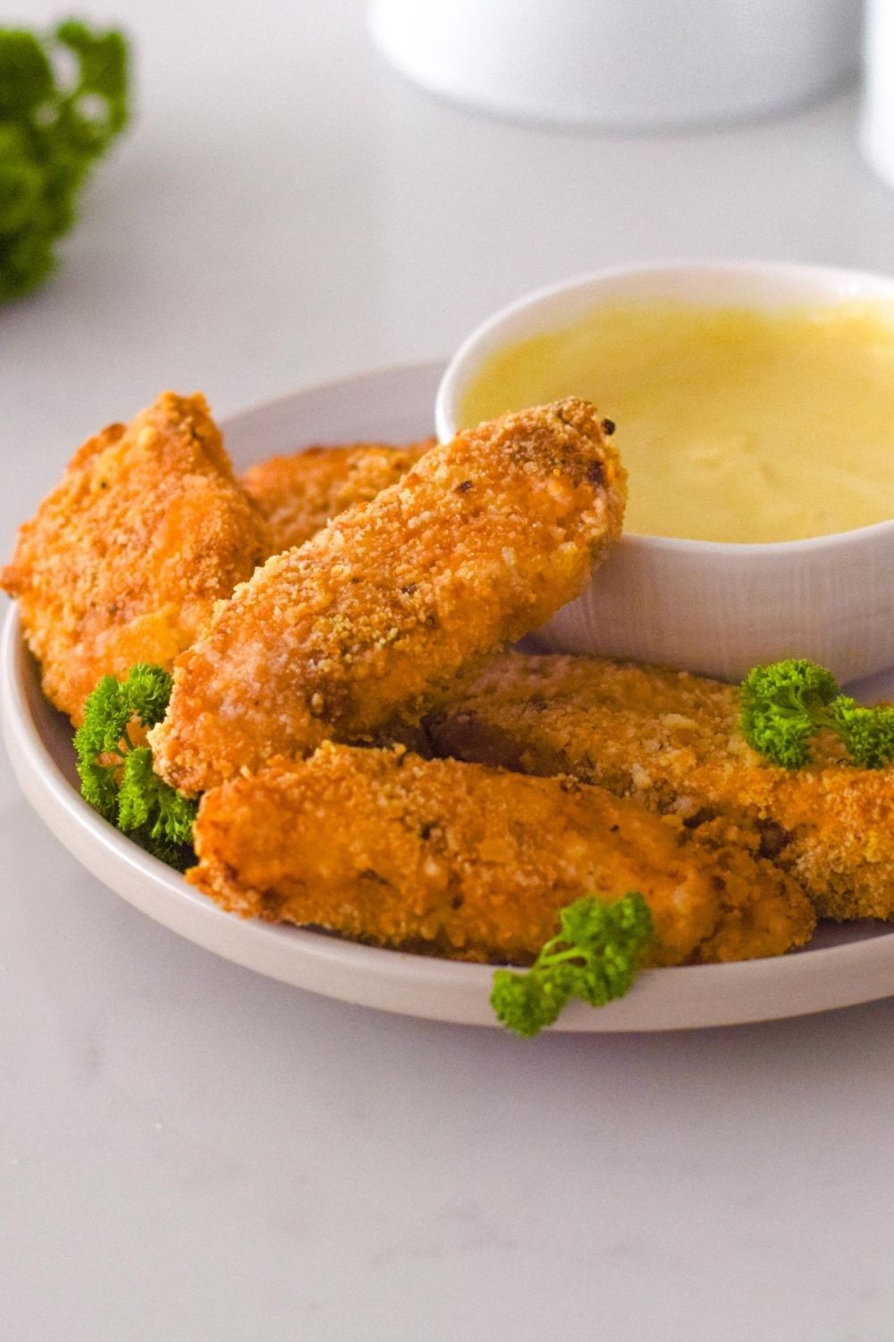 Chicken tenders crumbed with crackers on a white plate