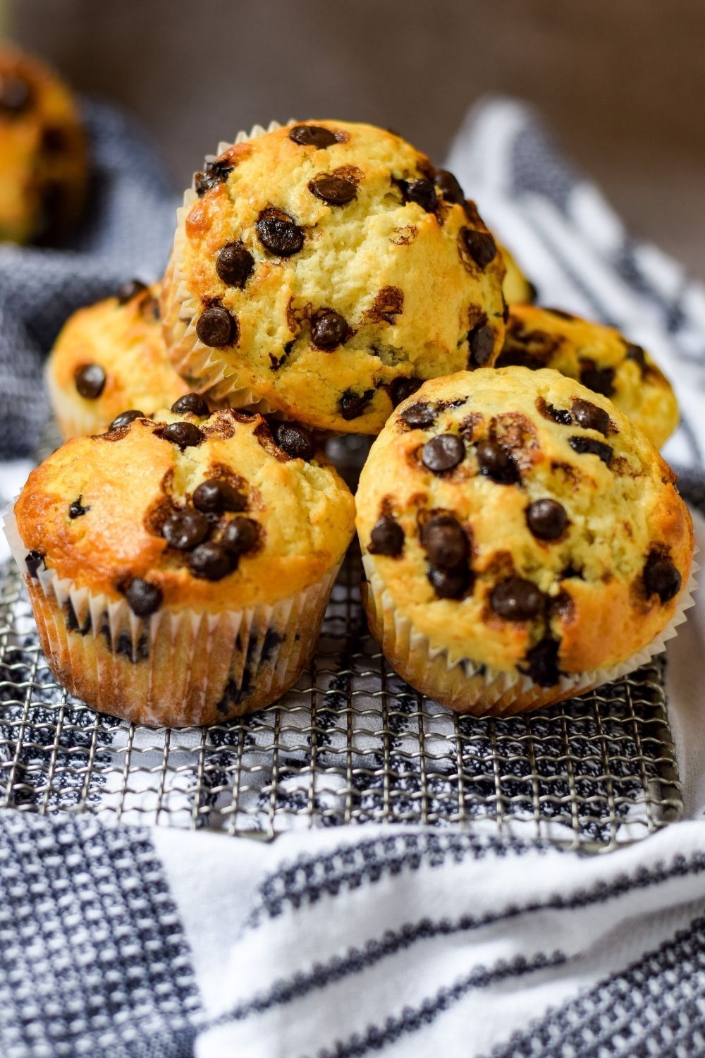 Vanilla Choc-Chip Muffins on a wire rack on top of a kitchen towel