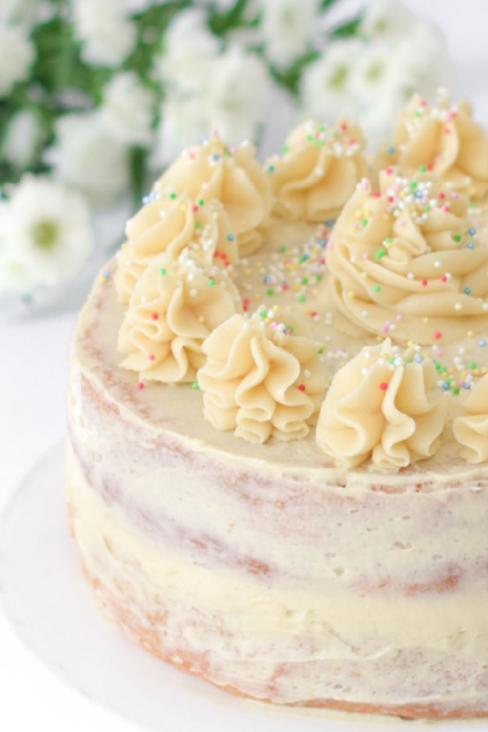 Eggless Vanilla Cake with flowers behind the cake