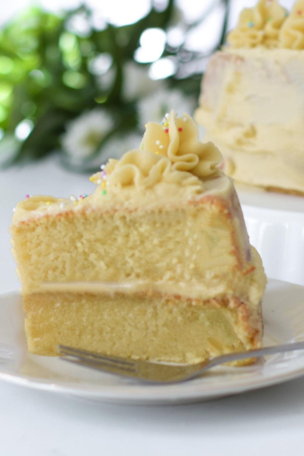 Slice of eggless vanilla cake on a white plate