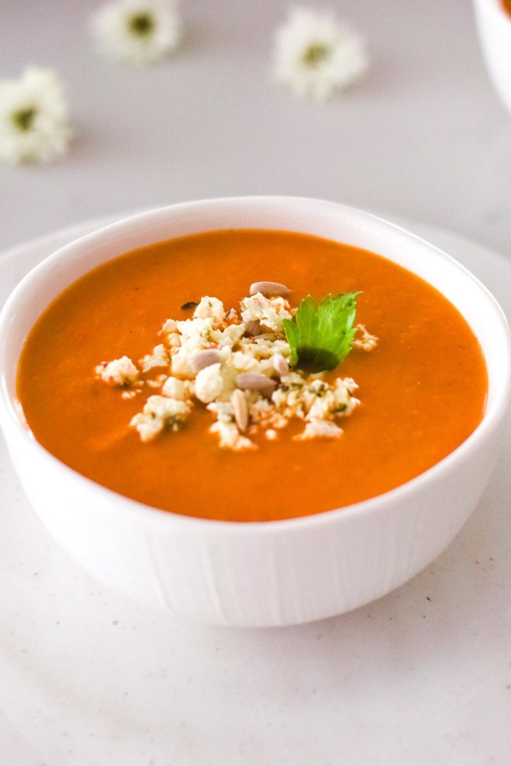 Tomato Coconut Soup in a white bowl with flowers on the left