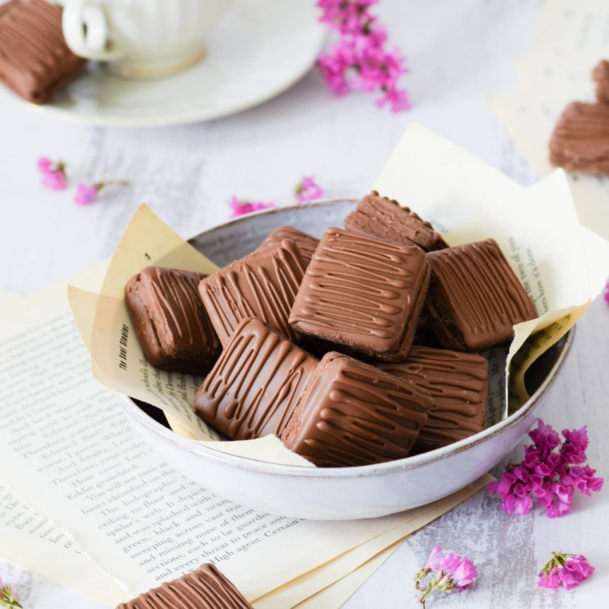 Eggless Chocolate Cookies in a white bowl with pink flowers scattered around
