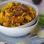 Soya Prawn Pilaf in a white bowl with 2 spoons on right and raita back right