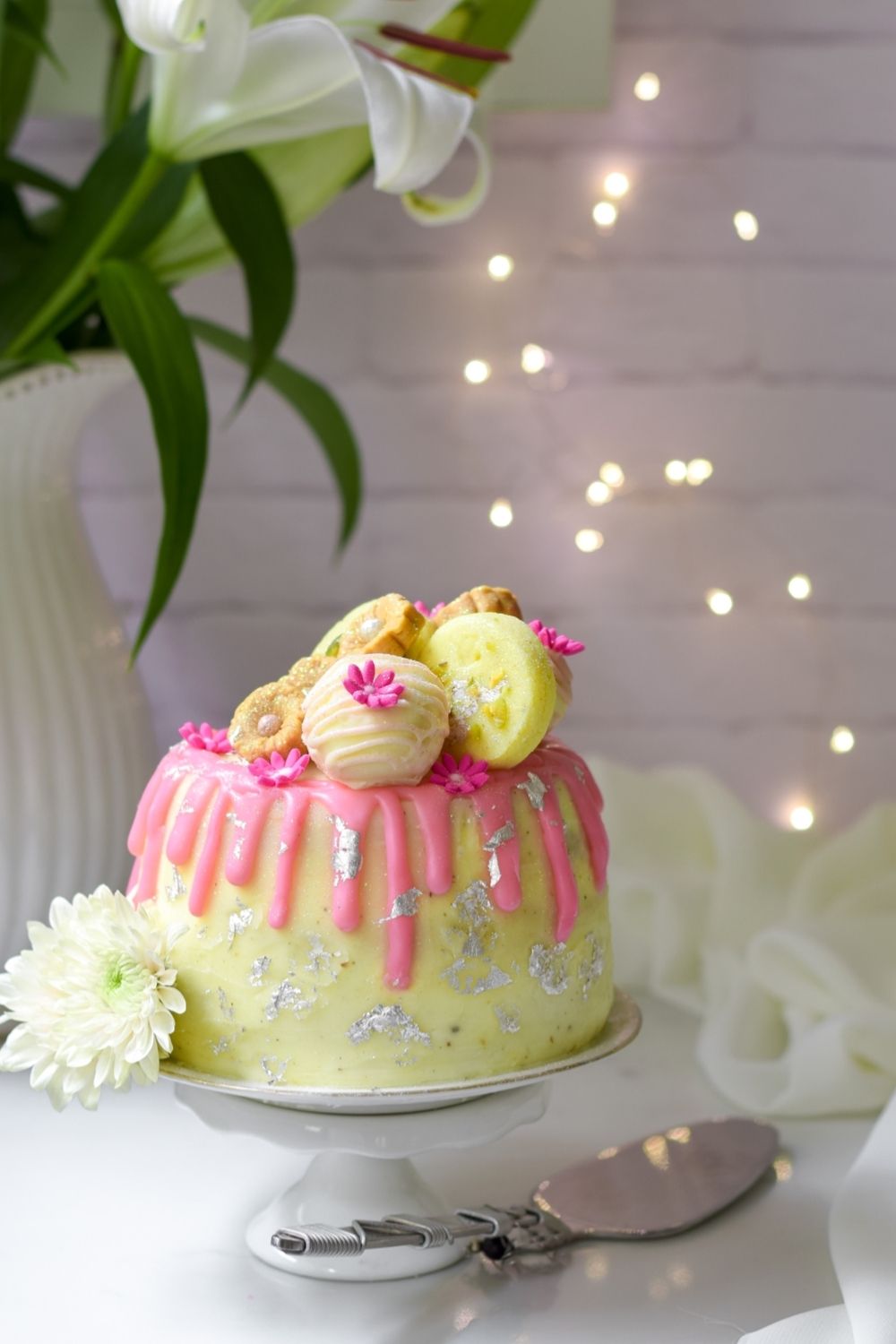 Eggless Burfee Cake on a cake stand with a cake lifter on right and plant at left back