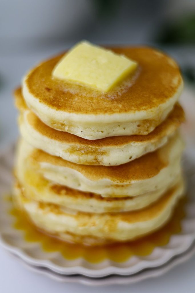 Flapjacks stacked on a plate with a blob of butter on top