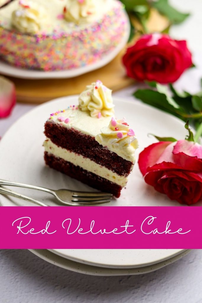 A slice of red velvet cake on a side plate with forks