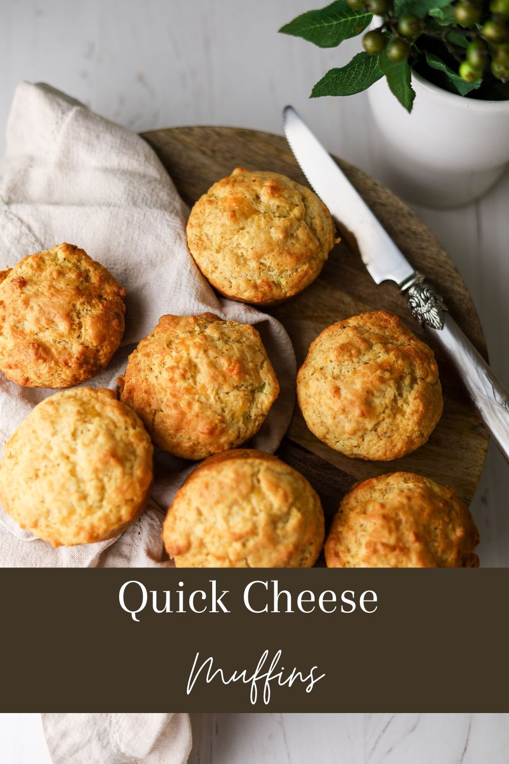 Cheese Muffins on a brown board with a knife on the right and napkin on the left