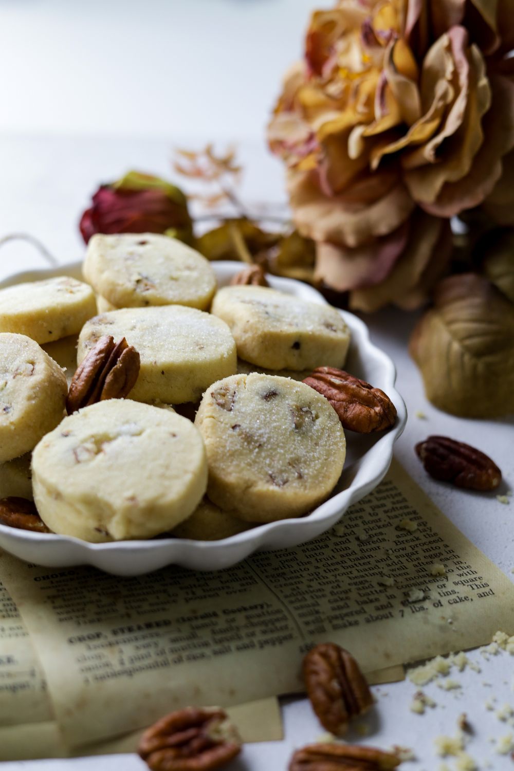 Pecan Shortbread Cookies in a white bowl with flowers on top right