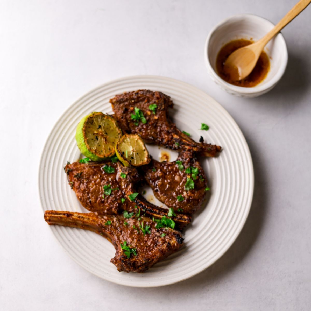 Braai Lamb Chops in a white plate with butter sauce on top right