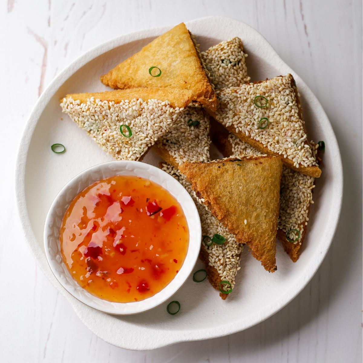 Prawn Toast in a white plate with sweet chilli sauce on left bottom